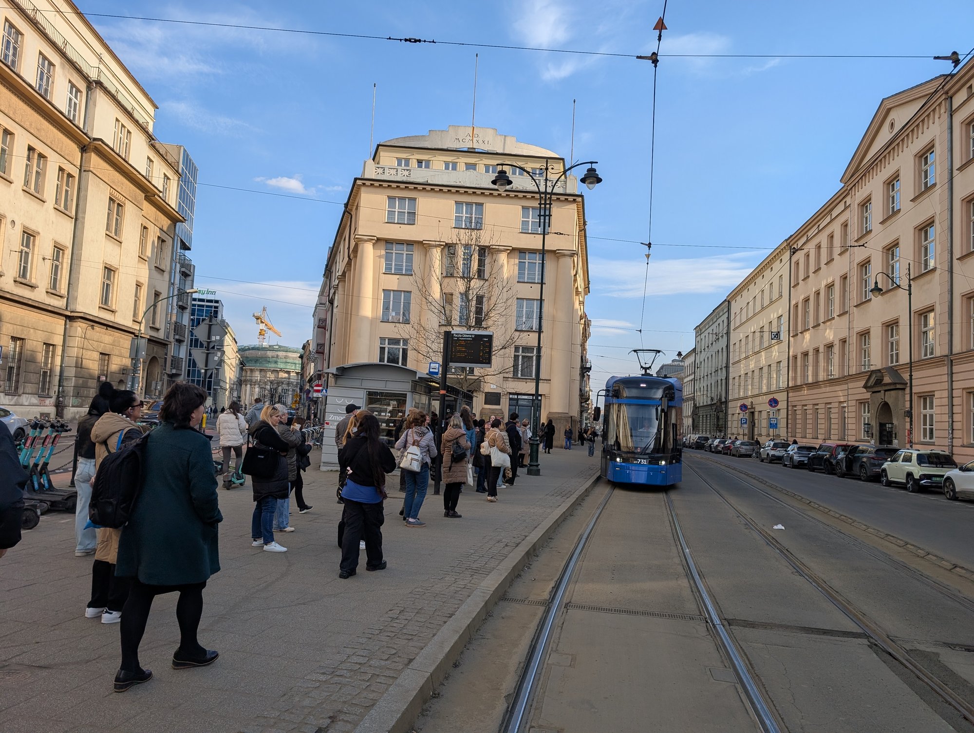 A blue MPK Krakow tram pulling into a crowded stop